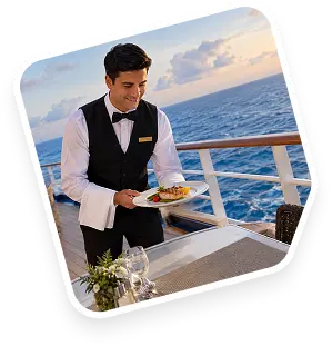 A waiter serving dinner on an open deck at sunset